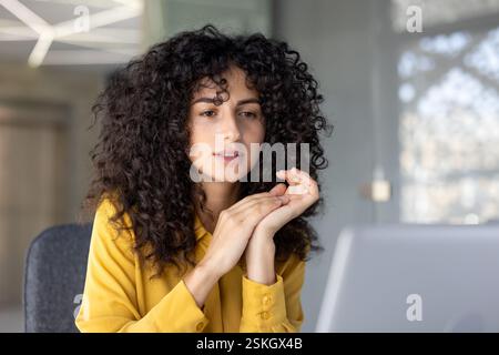 Thinking woman at workplace inside office working with laptop. Serious businesswoman reading data from computer screen close-up and watching educational video course. Stock Photo
