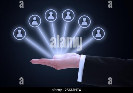 A hand in a suit holds seven user icons, symbolizing network management Stock Photo