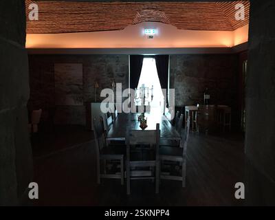Interior of a historic dining room, Braga, Portugal. Stone walls, vaulted ceiling, long wooden table. Rustic elegance. Glimpse into the past. Ideal fo Stock Photo