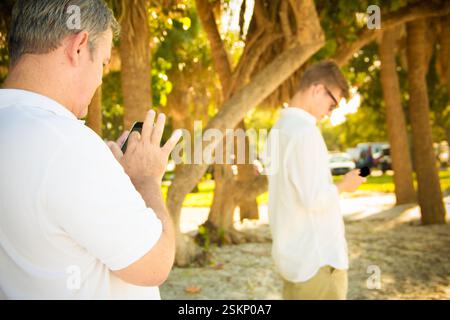 Two men standing outdoors using their mobile phones, Honduras Stock Photo