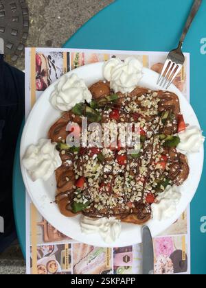 Waffle topped with whipped cream, strawberries, kiwi, chocolate spread, and chopped hazelnuts. Sweet and decadent dessert perfect for sharing. Indulge Stock Photo
