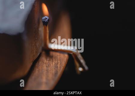 A single burning match sits on a wooden table, close up, macro photography Stock Photo