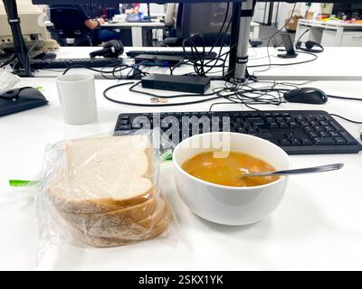 A bowl of soup, a working lunch sat at a desk in an office. Stock Photo