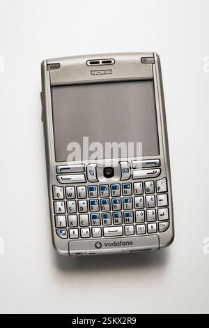 Retro Nokia E61 smartphone lying on a white background, showcasing its qwerty keyboard and Vodafone branding Stock Photo