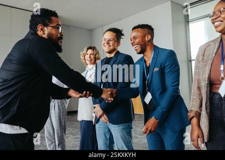 Diverse group of professionals greeting each other with handshakes at a corporate conference event in an office setting. Stock Photo