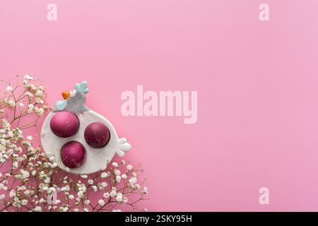 Spring Easter background, multi-colored Easter eggs in a decorative hen with gypsophila flowers on a pink background, copy space Stock Photo