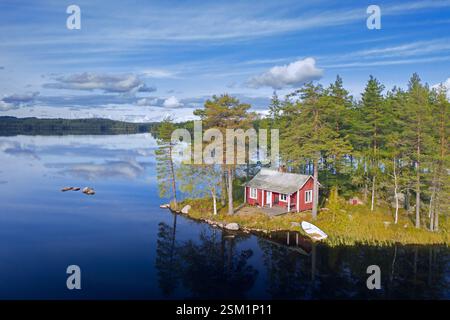 Lonely small traditional red wooden cabin along lake shore in autumn / fall, Värmland, west-central Sweden, Scandinavia Stock Photo