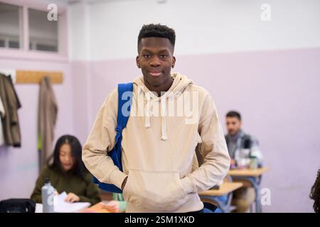 Confident male student standing in classroom at university institute Stock Photo