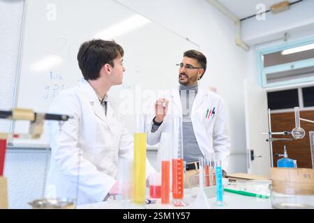 Chemistry teacher explaining experiment to student in laboratory Stock Photo