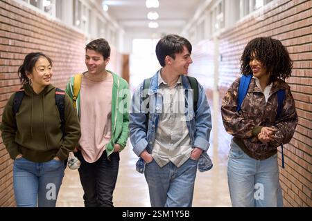 Happy students walking and talking in university hallway Stock Photo