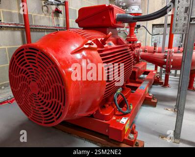 A close-up view of a large industrial fire pump motor painted red. The pump system is part of a fire suppression system. Stock Photo