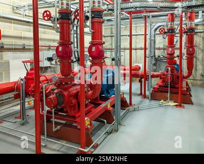 Industrial fire pump room with electric fire pumps, pipework, valves and fire suppression system in a commercial building. Stock Photo