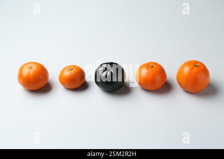 Stop racism. One black tangerine among orange ones on light background Stock Photo