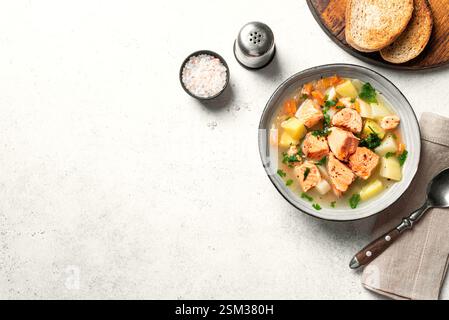 Salmon fish soup isolated on white background, top view, copy space. Traditional homemade soup with red salmon and vegetables. Stock Photo