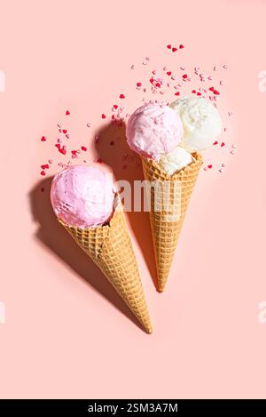 Two ice cream cones with heart shaped sugar sprinkles on pink pastel background, top view, copy space. Valentines day, sweet love and funny summer des Stock Photo