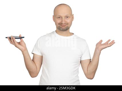 A bald Caucasian man with light stubble is wearing a white t-shirt and holding a smartphone in one hand while shrugging. Stock Photo