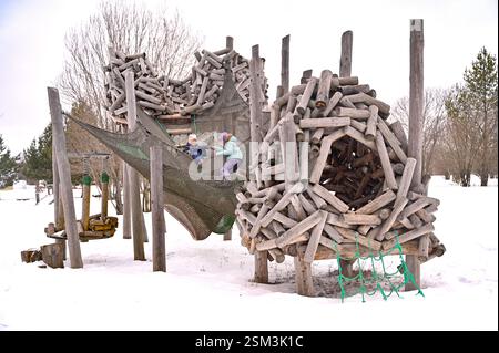 Children playing in winter on a modern wooden playground Stock Photo