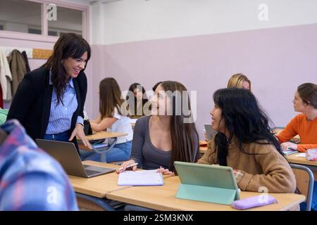 Teacher helping students studying on their laptops in classroom Stock Photo