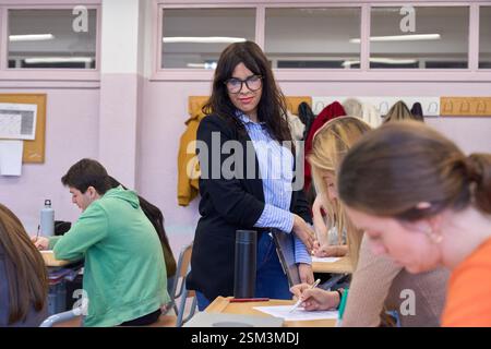 University professor supervising students taking exam in classroom Stock Photo