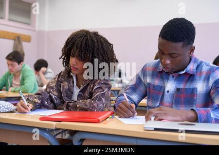 University students taking exam, writing notes in classroom Stock Photo
