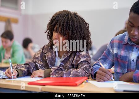 Focused students writing exam in university classroom Stock Photo