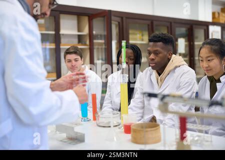 Chemistry teacher explaining experiment to students in laboratory Stock Photo
