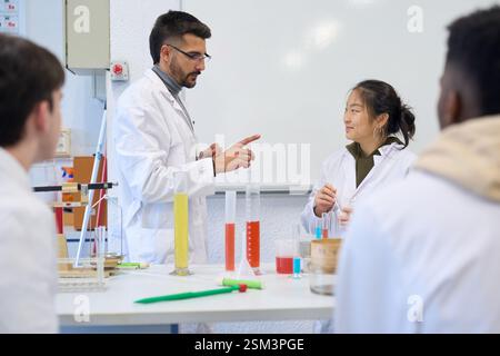 Chemistry teacher explaining experiment to students in laboratory Stock Photo