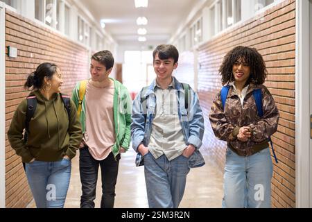 Happy students walking and talking in university hallway Stock Photo