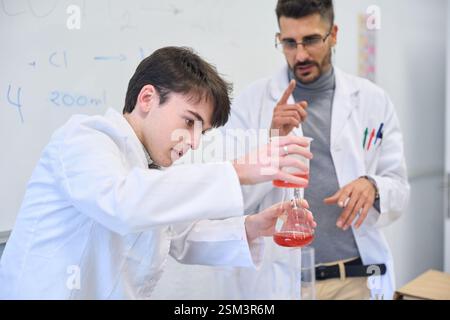 Chemistry student pouring liquid into beaker during experiment at university institute Stock Photo