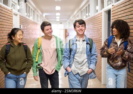 Happy students walking and talking in university hallway Stock Photo