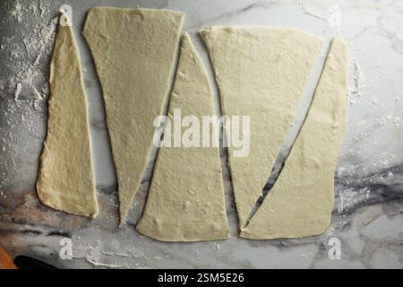 Roll out the dough and cut into triangles for the croissant. Stock Photo