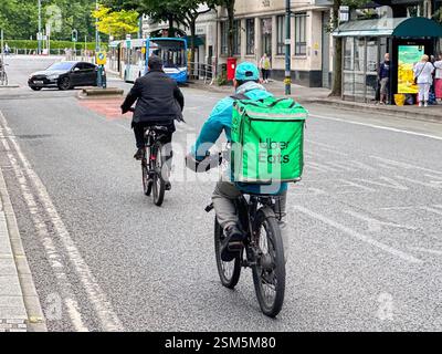 Cardiff, Wales - 24 July 2024: Cyclist on a street in Cardiff city centre delivering takeaway food for Uber Eats Stock Photo