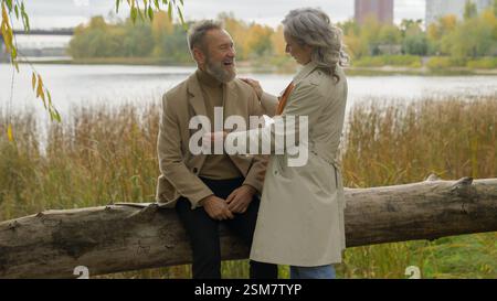 Happy family Caucasian mid age couple female male rest together autumn weekend senior man talking to mature woman two grandparents laughing having fun Stock Photo