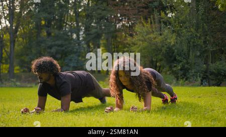 Fitness couple diverse Arabian man Caucasian woman doing sport morning practice city park nature outside workout sporty strong sportsman sportswoman Stock Photo