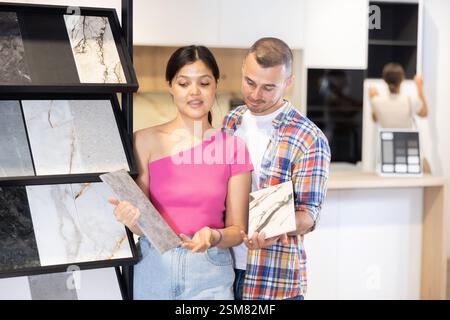 Couple discussing tile samples displayed on racks in home improvement store Stock Photo