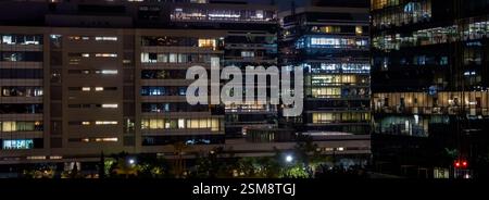 Office windows in high-rise buildings at night Stock Photo