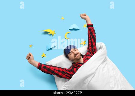 Handsome young man with sleep mask stretching in bed on blue background Stock Photo