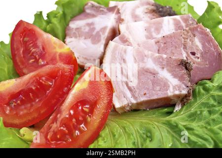 Several pieces of bacon, three slices of tomato on lettuce leaf isolated on a white background Stock Photo