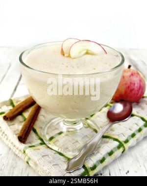 Air apple jelly in a glass bowl, red apples and cinnamon on a towel on the background light wooden boards Stock Photo