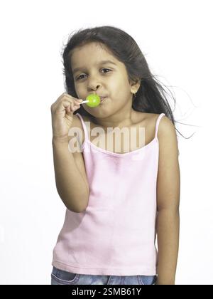 South Asian Indian girl sucking lollipop in nursery school MR Stock