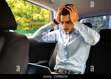 Worried middle eastern businessman using laptop in car Stock Photo