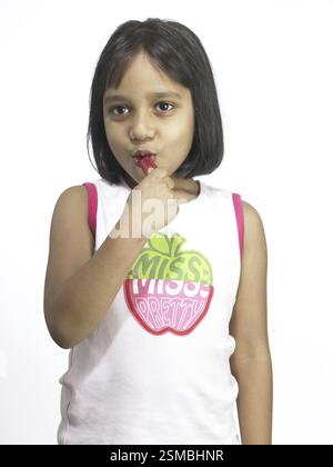 South Asian Indian girl sucking lollipop in nursery school MR Stock