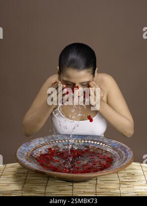 South Asian Indian woman splashing rose petals water on her face MR # 702 Stock Photo
