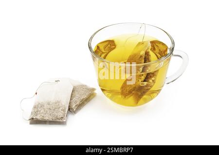 Green herbal tea from a bag in a glass cup, two sachets of herbal tea isolated on a white background Stock Photo