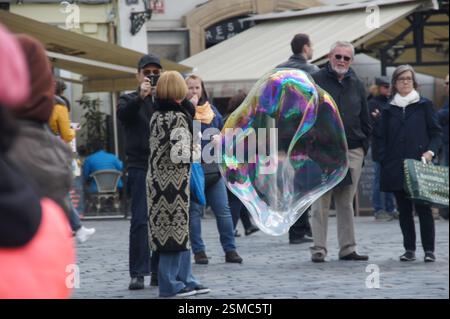 playing outdoors, holding a magic bubble wand. The wand is dipped into a soap solution, creating large, iridescent bubbles that float gently through t Stock Photo