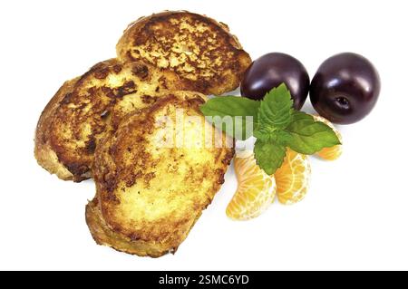 Three golden fried toast, two plums, three segments of mandarin, mint sprig isolated on a white background Stock Photo
