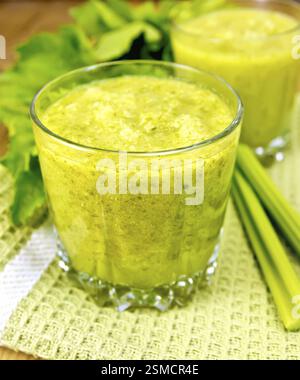 Two glassful with a cocktail of celery on green napkin, stems and leaves of celery on a wooden boards background Stock Photo