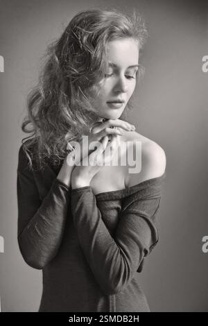 Portrait of beautiful blonde woman with long curly hair at the window. Natural daylight. Monochrome image Stock Photo