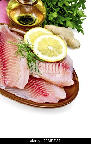 Tilapia fillets with dill, parsley and lemon in a clay pot, a bottle of vegetable oil, ginger, pink napkin isolated on white background Stock Photo