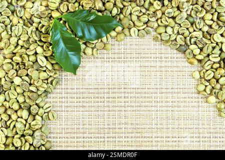 Frame of green coffee beans with leaves on a yellow coarse woven fabric Stock Photo